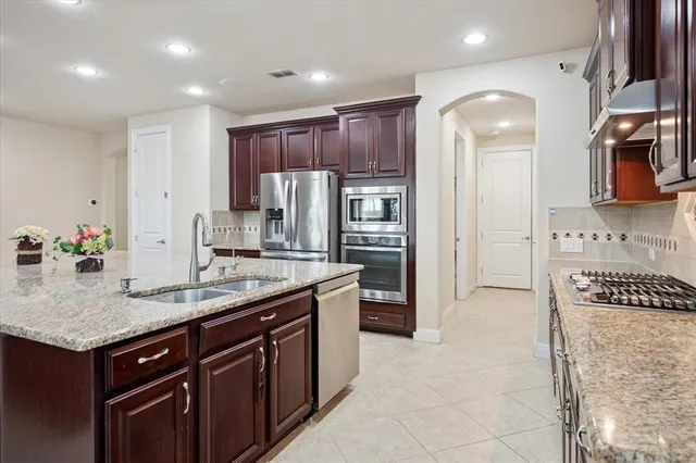 a kitchen with kitchen island granite countertop a sink and a refrigerator