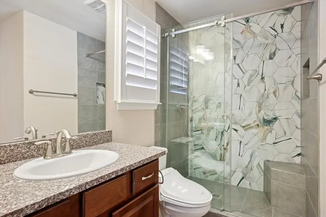 a bathroom with a granite countertop sink toilet a mirror a shower and a sink