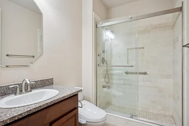 a bathroom with a granite countertop sink toilet mirror and shower
