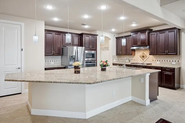 a kitchen with stainless steel appliances granite countertop a sink a stove and a refrigerator