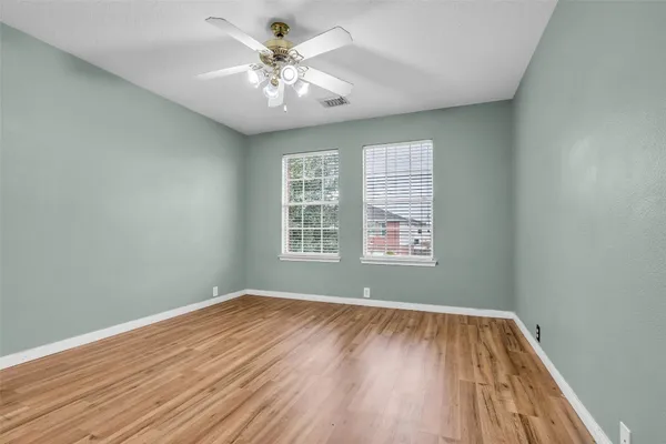 an empty room with wooden floor and windows