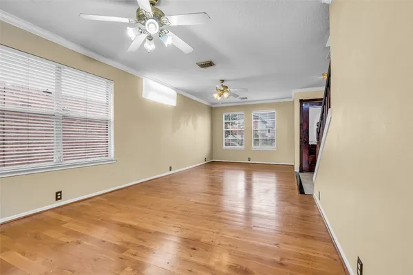 a view of an empty room with a window and wooden floor