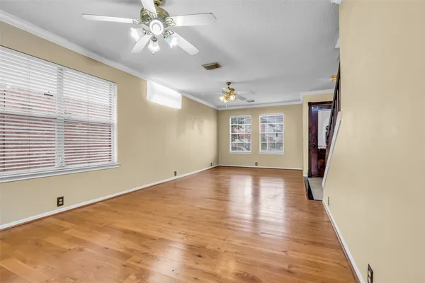 a view of an empty room with a window and wooden floor
