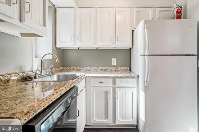 a kitchen with granite countertop a sink cabinets and stainless steel appliances