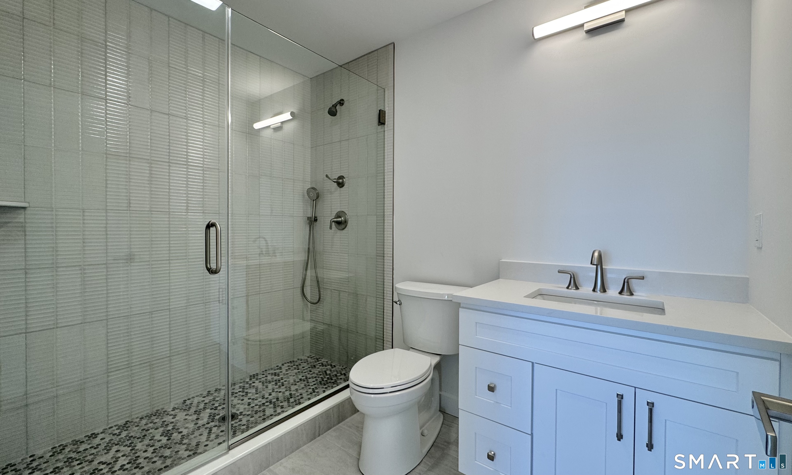 25 Village Road Milford, CT 06460 - Photo 15 of 27 a bathroom with a granite countertop toilet a sink a mirror and shower