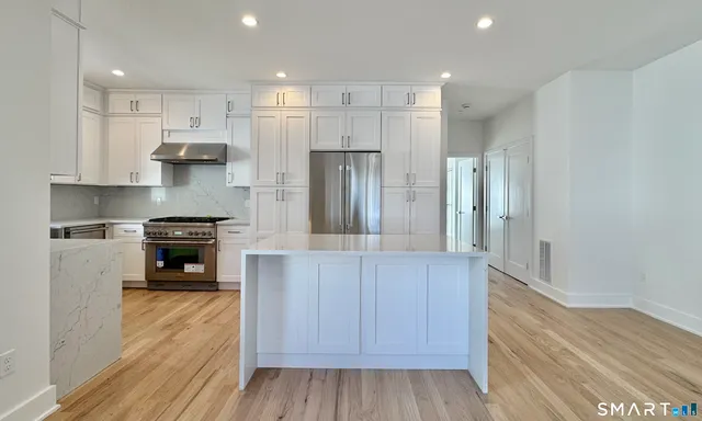 a kitchen with stainless steel appliances granite countertop a refrigerator and a stove
