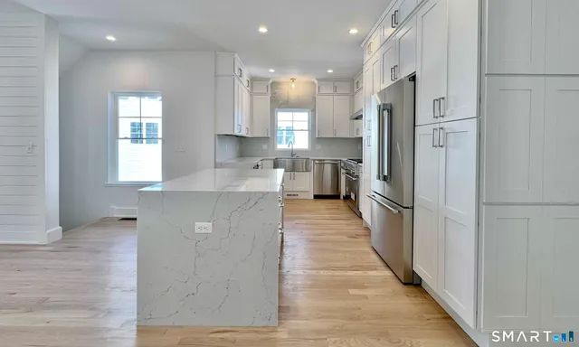 a large kitchen with stainless steel appliances kitchen island granite countertop a refrigerator and a sink