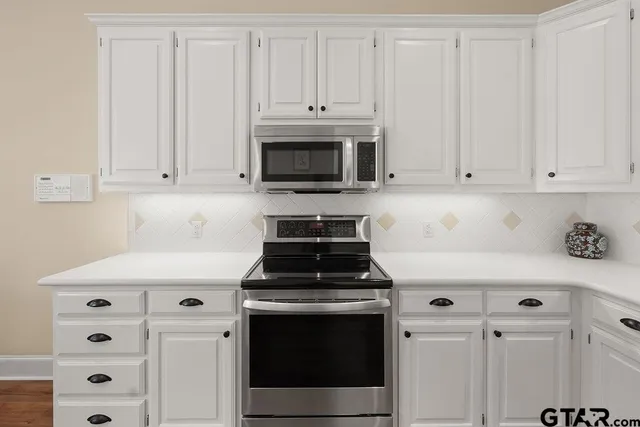 a kitchen with white cabinets and stainless steel appliances