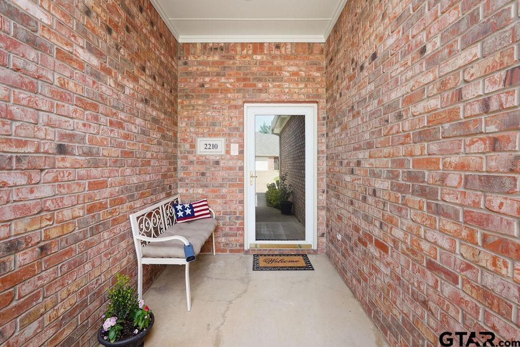 2210 Homestead Lane Tyler, TX 75701 - Photo 3 of 26 a brick building with a bench and a potted plant