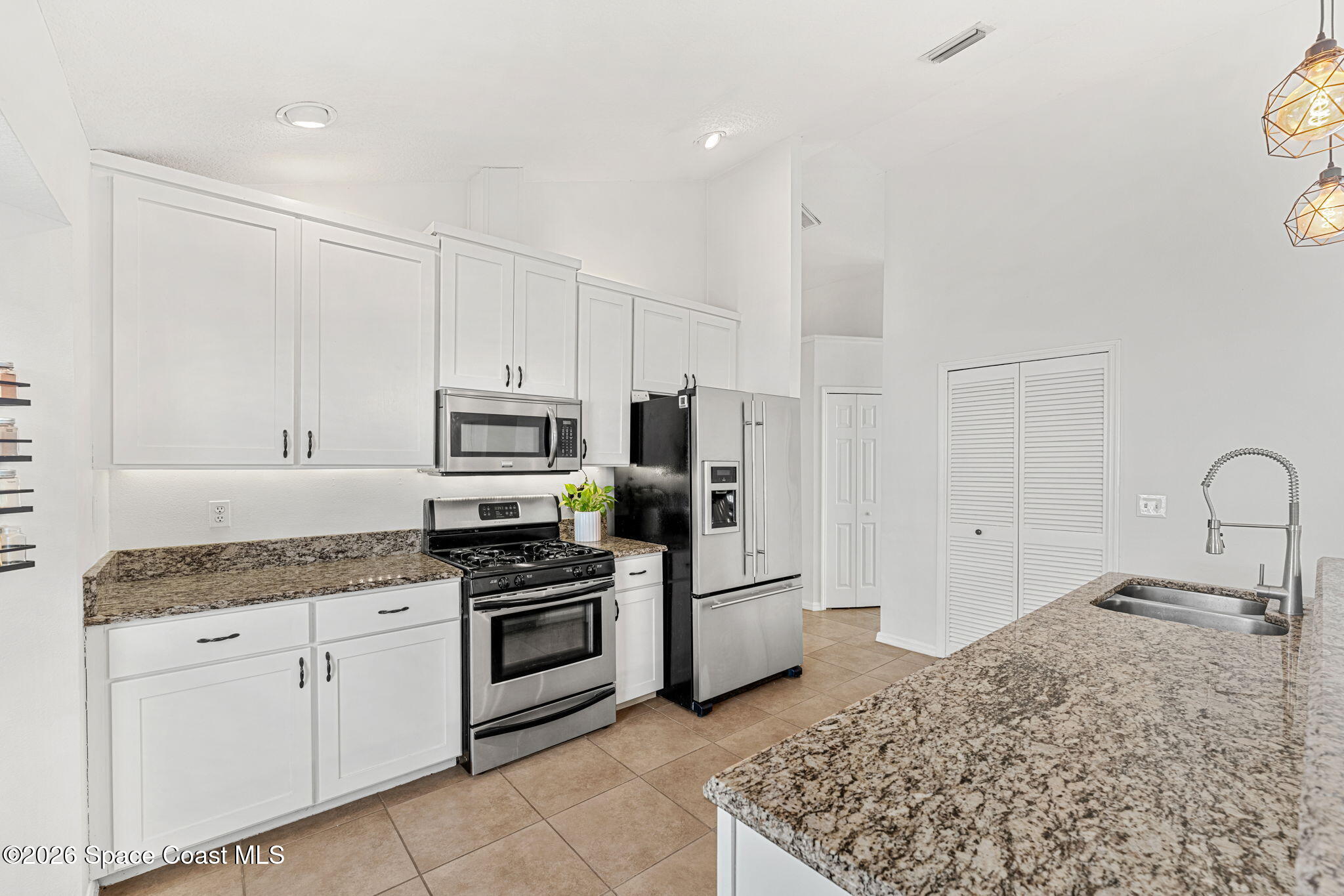1924 Fabien Circle Melbourne, FL 32940 - Photo 11 of 35 a kitchen with white cabinets and stainless steel appliances