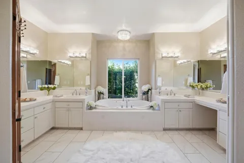 a large white bathroom with a sink a large mirror and a bathtub