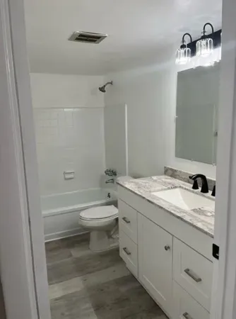 a bathroom with a granite countertop toilet a sink and a mirror