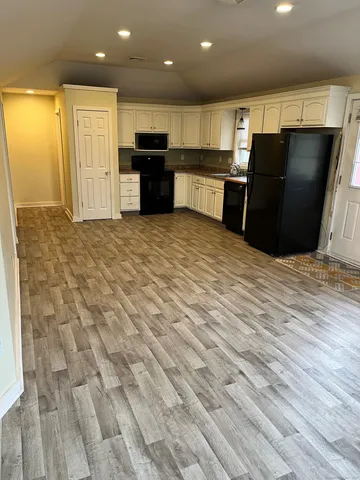 a large kitchen with stainless steel appliances kitchen island granite countertop a refrigerator and a sink