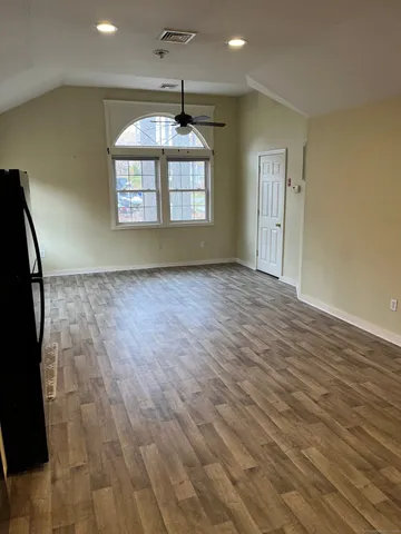 an empty room with wooden floor chandelier and windows