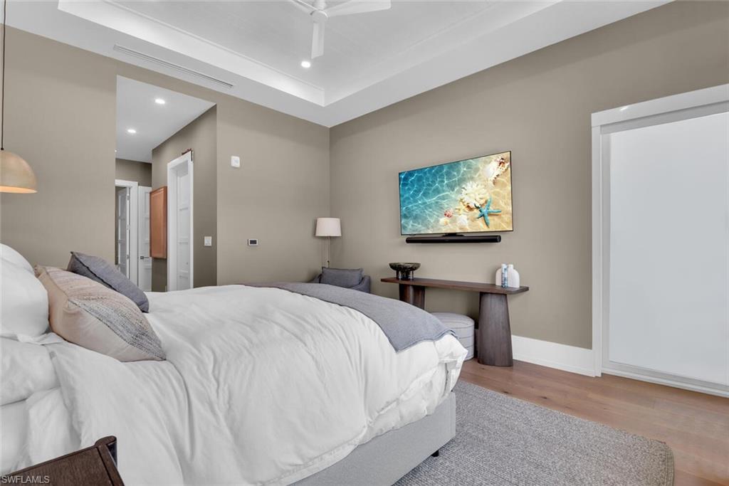 201 8th Street South, Unit 311 Naples, FL 34102 - Photo 17 of 39 Bedroom with wood finished floors, a tray ceiling, baseboards, recessed lighting, and ceiling fan