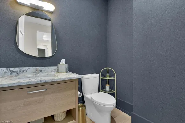 a bathroom with a toilet sink vanity and mirror