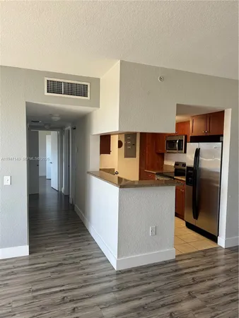 a kitchen with stainless steel appliances granite countertop a refrigerator a stove and a wooden floors