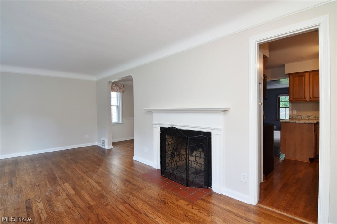 5284 Edenhurst Road Lyndhurst, OH 44124 - Photo 6 of 50 Hardwood flooring, white crown molding, fireplace with white mantel, tiled hearth, and decorative fire screen