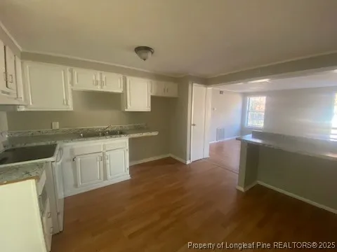 a kitchen with granite countertop white cabinets and wooden floor