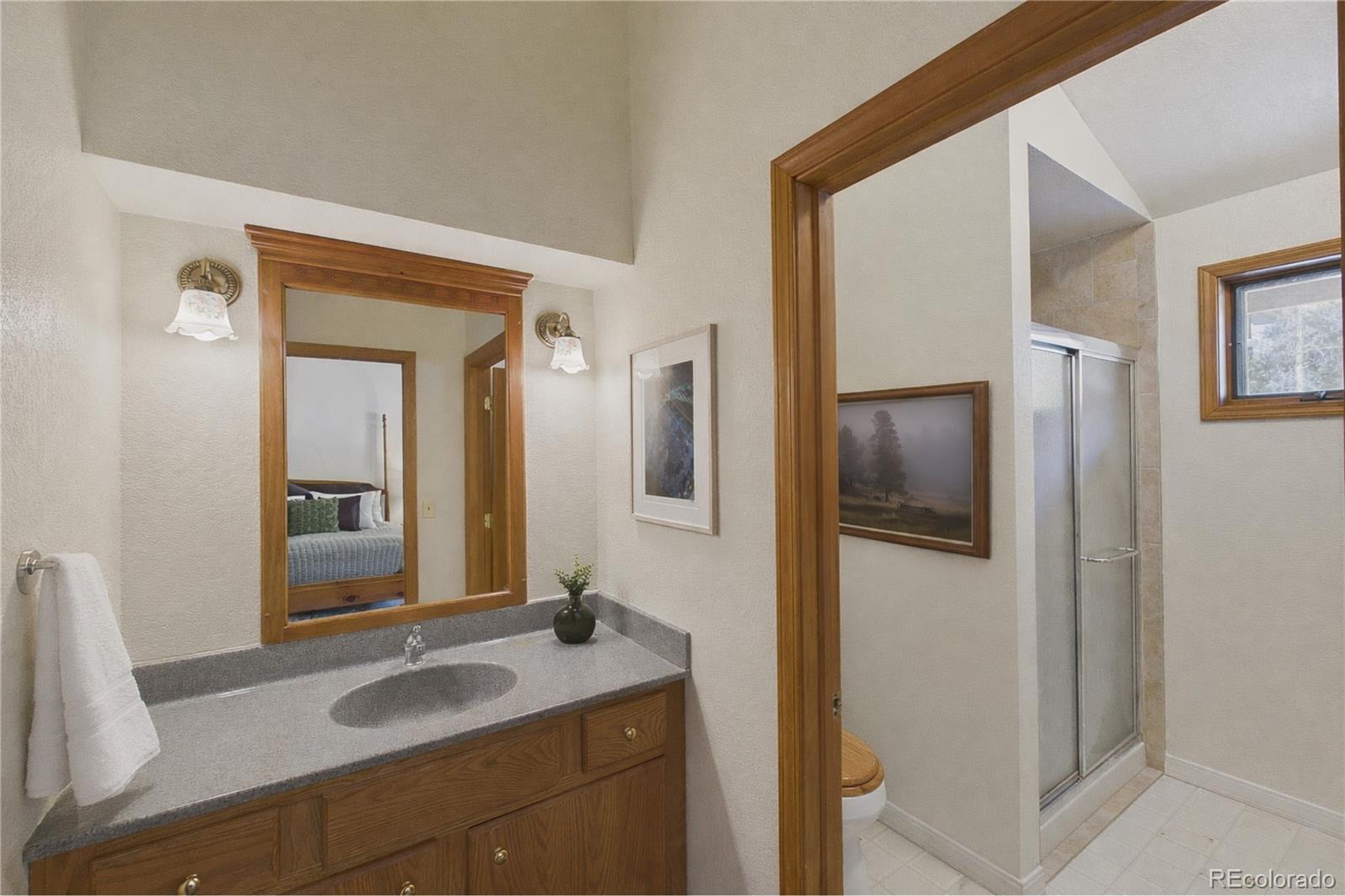 10798 Crystal Way Morrison, CO 80465 - Photo 18 of 36 a en suite bathroom with a granite countertop sink and a mirror