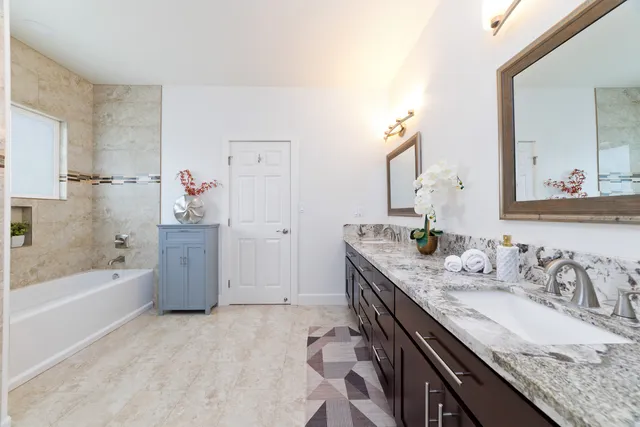a bathroom with a granite countertop sink a mirror a bathtub and shower