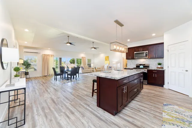 a large kitchen with stainless steel appliances granite countertop a stove oven a dining table and chairs with wooden floor