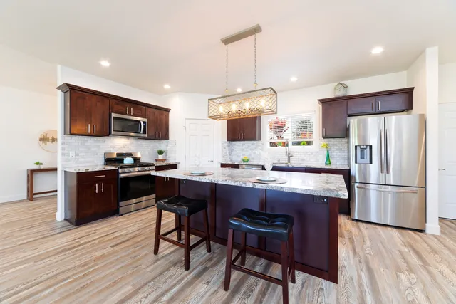 a kitchen with a refrigerator a stove a sink dishwasher with a dining table and chairs