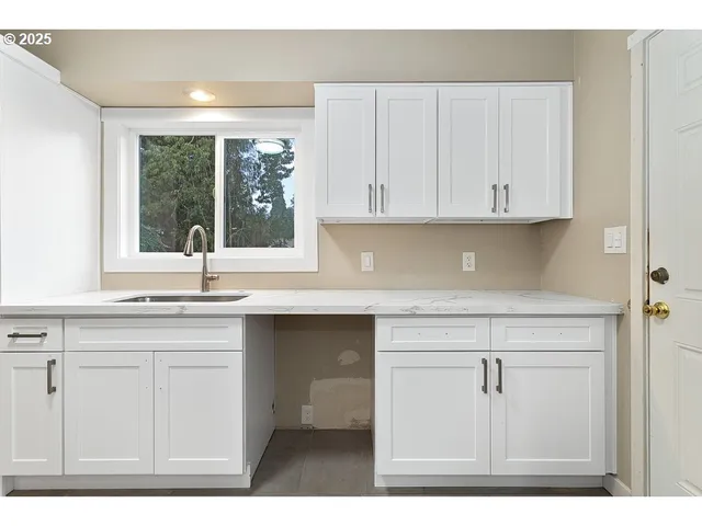 a kitchen with granite countertop white cabinets and a window