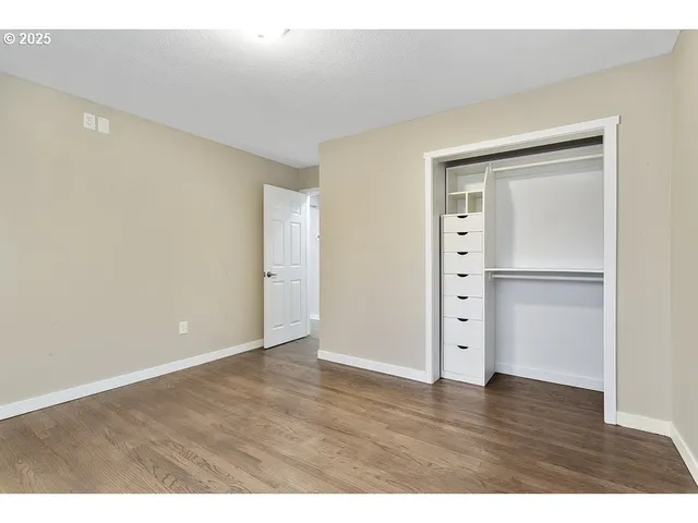 a view of an empty room with wooden floor and closet