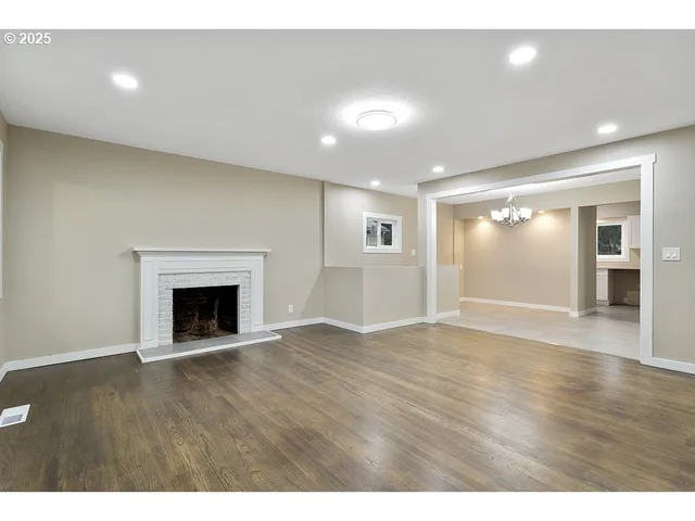 a view of an empty room with wooden floor and a fireplace