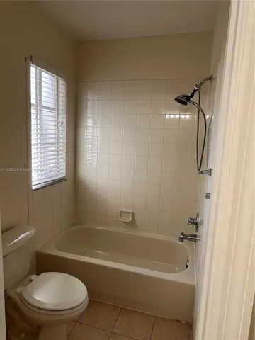 a bathroom with a toilet bathtub window and shower