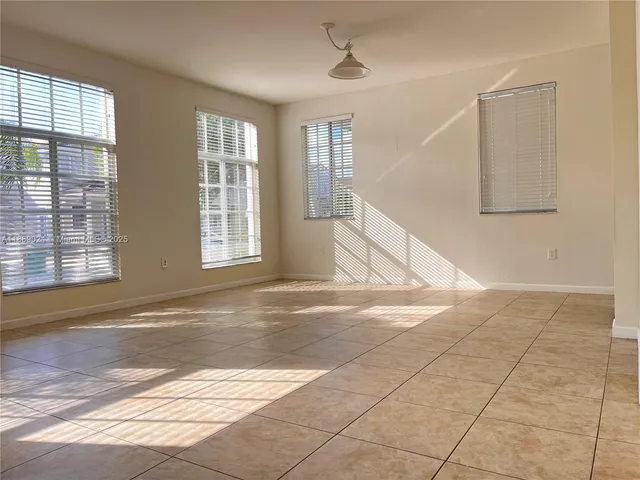 a view of an empty room with a window and a kitchen