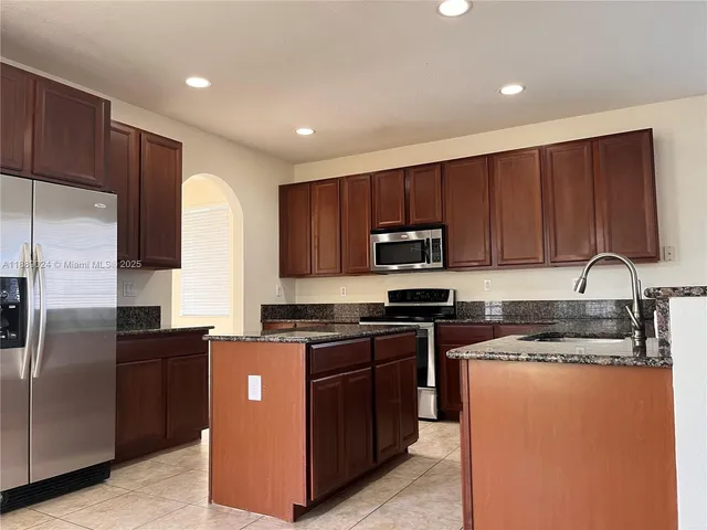 a kitchen with stainless steel appliances granite countertop a stove a sink dishwasher a refrigerator and cabinets with wooden floor