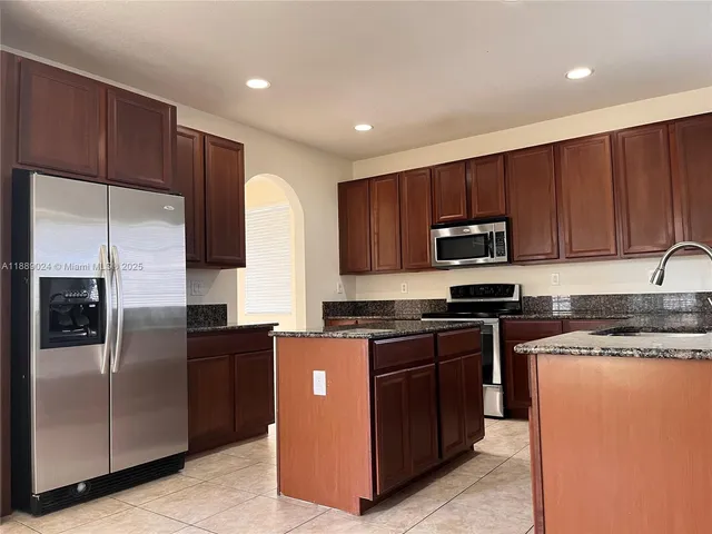 a kitchen with stainless steel appliances granite countertop a stove a refrigerator and a sink