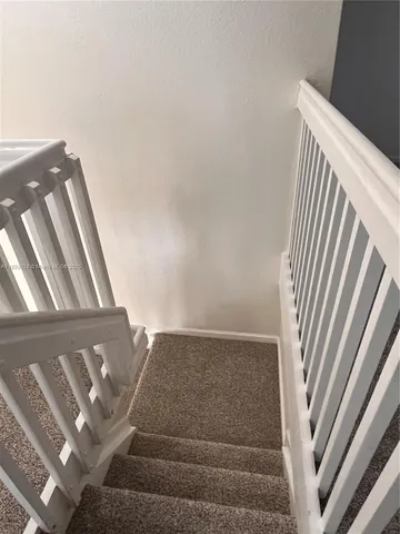 a view of staircase with white walls and white door