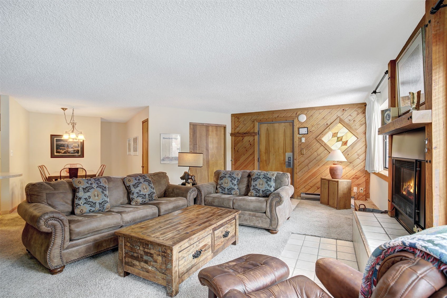 400 4 O Clock Road, Unit A Breckenridge, CO 80424 - Photo 5 of 31 Living room with wood walls, a textured ceiling, carpet flooring, and a glass covered fireplace