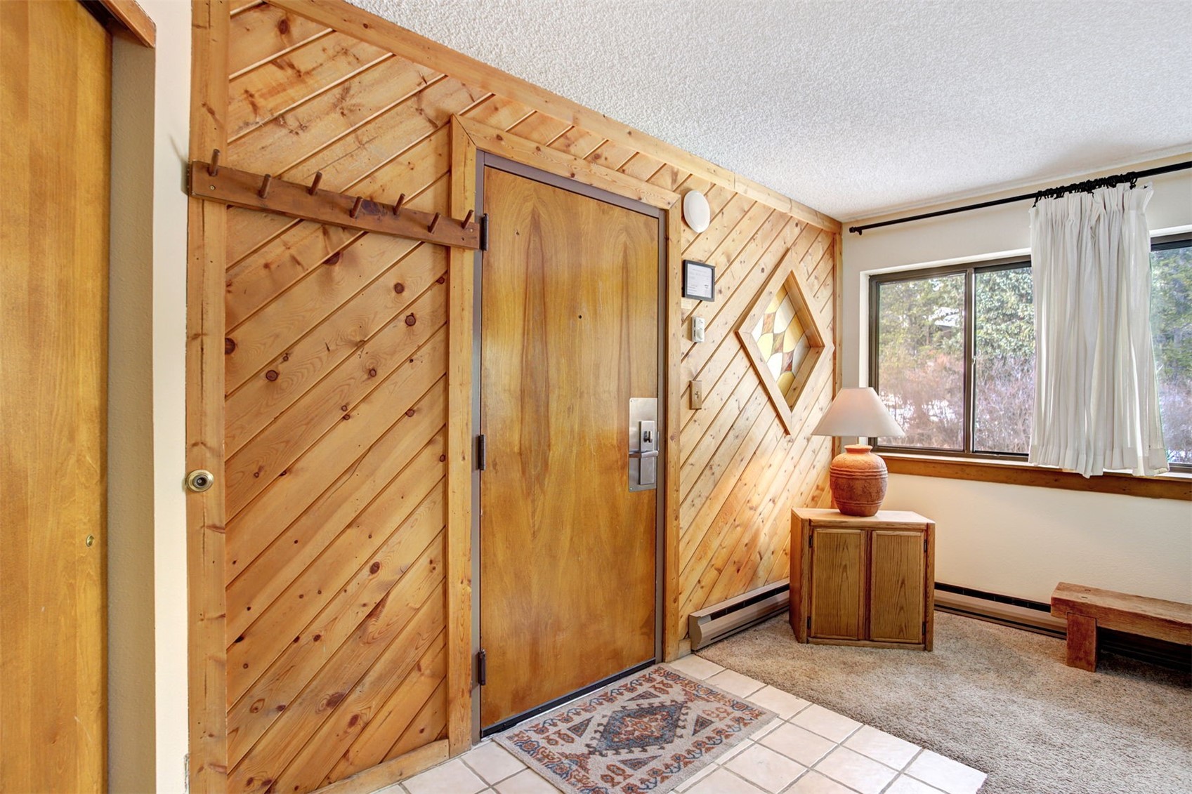 400 4 O Clock Road, Unit A Breckenridge, CO 80424 - Photo 8 of 31 Tiled entrance foyer featuring a textured ceiling, wood walls, baseboard heating, a baseboard radiator, and carpet floors