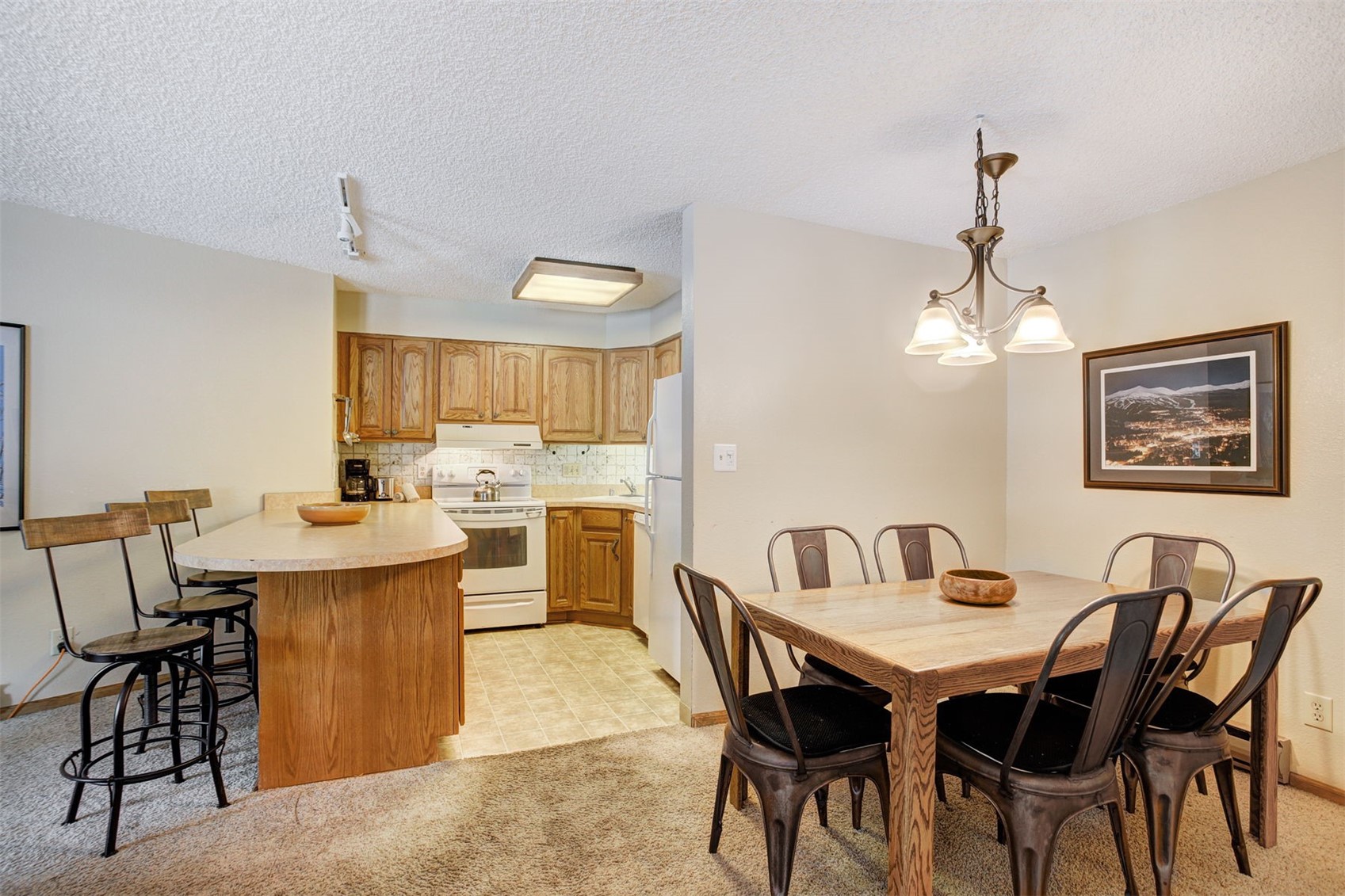 400 4 O Clock Road, Unit A Breckenridge, CO 80424 - Photo 9 of 31 Dining room featuring a textured ceiling, light colored carpet, a chandelier, and a baseboard radiator