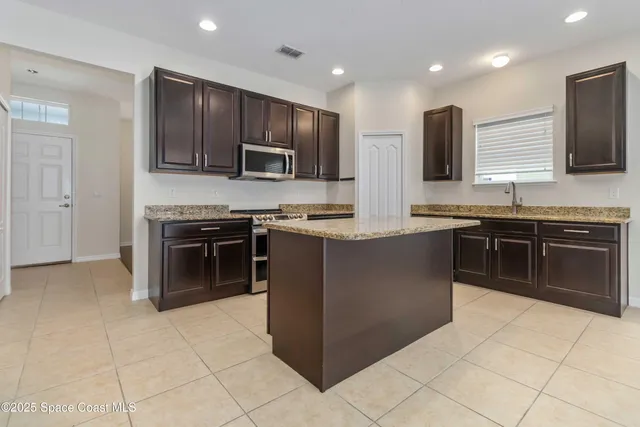 a kitchen with stainless steel appliances granite countertop a stove top oven a sink and a microwave