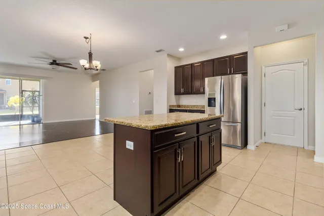 a kitchen with kitchen island granite countertop a refrigerator and a sink