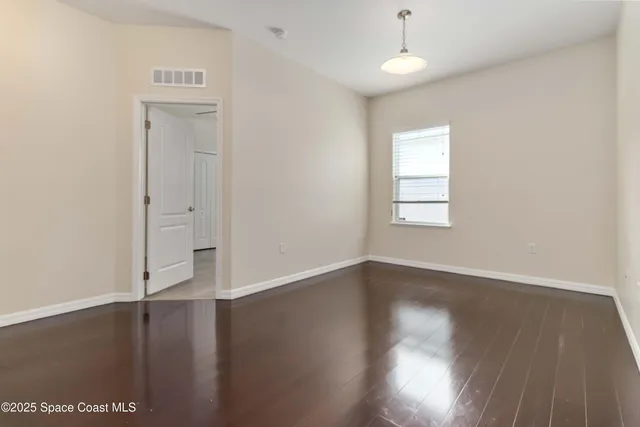 an empty room with wooden floor cabinet and windows