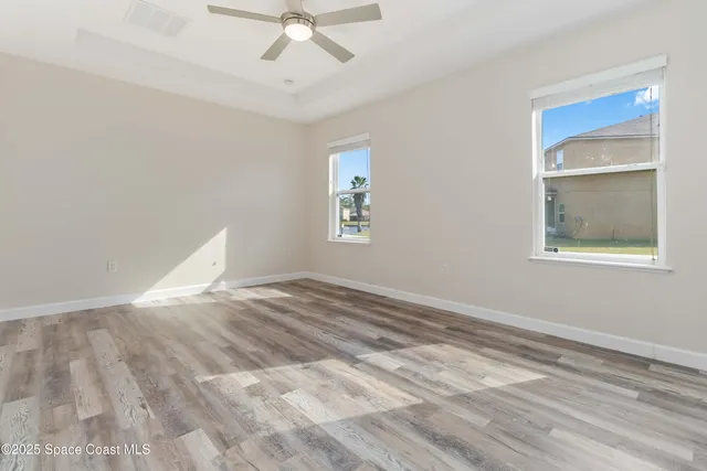 a view of empty room with wooden floor and fan