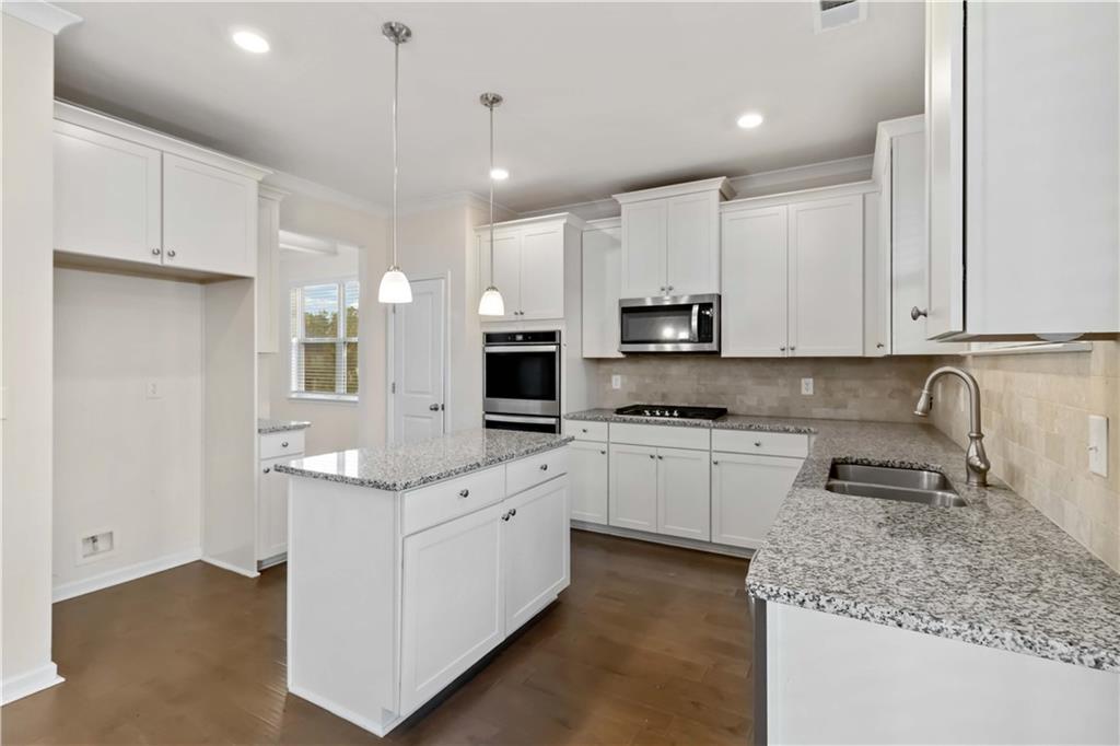 156 Beaumont Way Hampton, GA 30228 - Photo 10 of 21 a kitchen with kitchen island granite countertop a sink white cabinets and white appliances