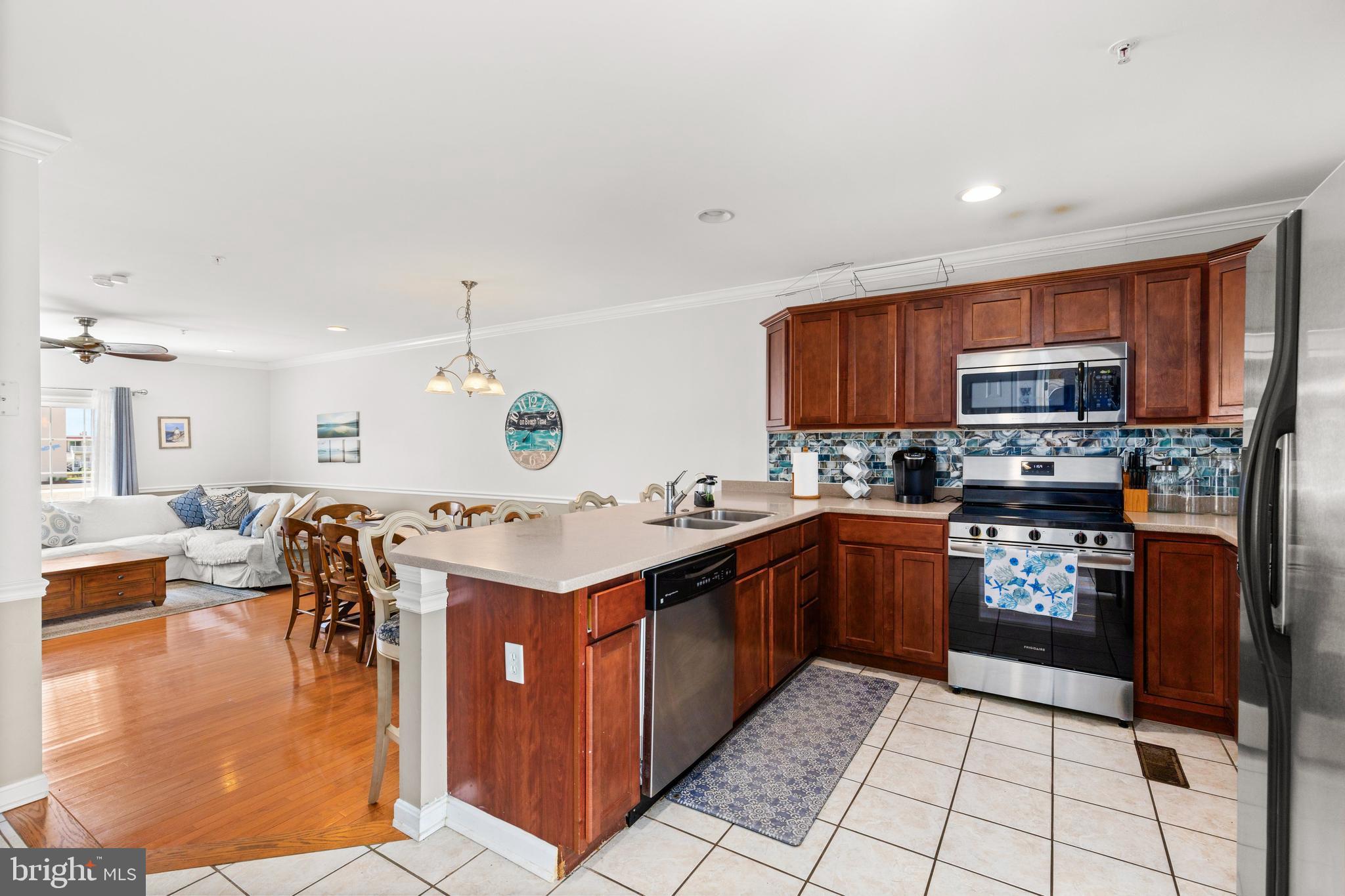 617 Salt Spray Road, Unit B Ocean City, MD 21842 - Photo 25 of 72 a kitchen with stainless steel appliances granite countertop a stove top oven a sink dishwasher a dining table and chairs with wooden floor