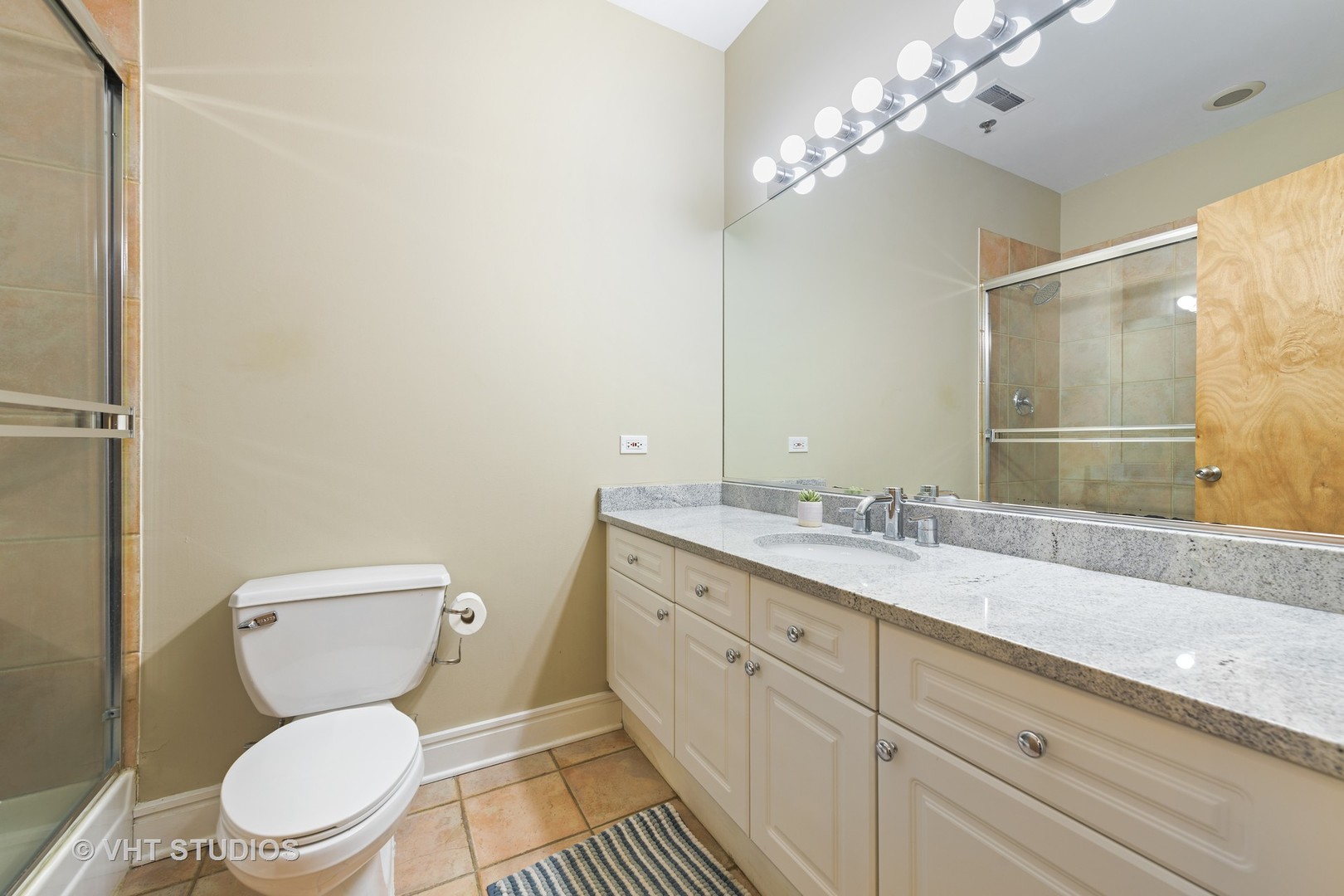 212 West Washington Street, Unit 1002 Chicago, IL 60606 - Photo 8 of 12 a bathroom with a granite countertop toilet sink and mirror
