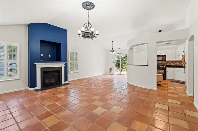a view of a livingroom with a fireplace a chandelier and windows