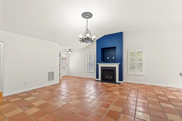 a view of a livingroom with a fireplace a chandelier and windows