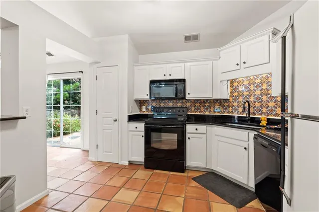 a kitchen with granite countertop white cabinets and black appliances