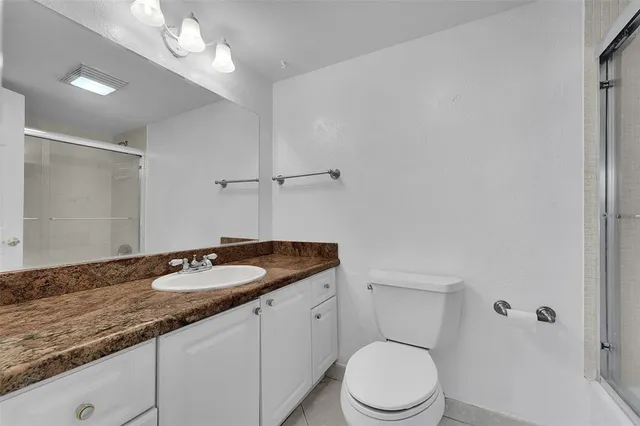 a bathroom with a granite countertop sink a toilet and a mirror