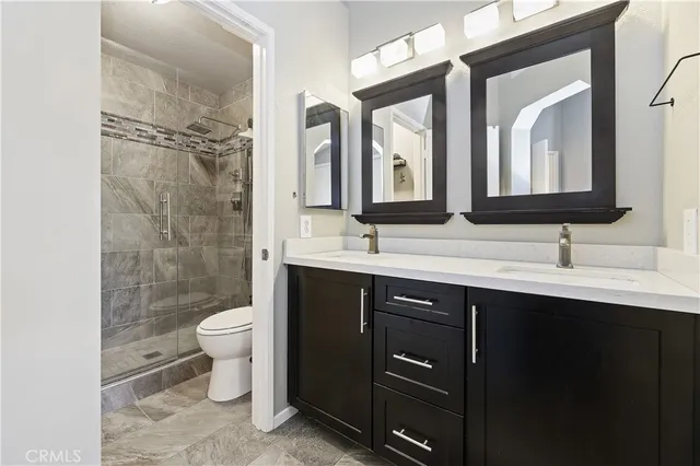a bathroom with a toilet sink double vanity and mirror